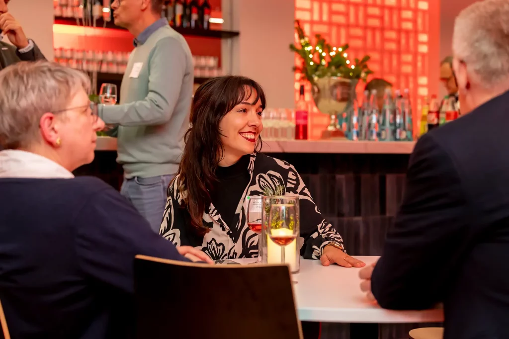 Frau redet am Tisch mit zwei Maennern