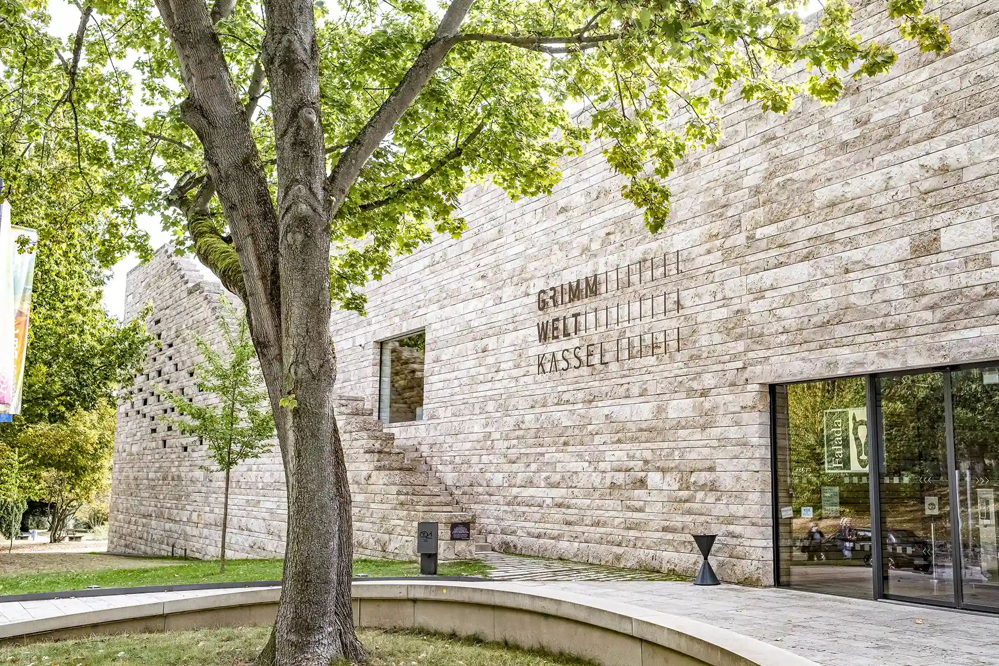 Haupteingang der Grimmwelt Kassel mit einem Baum im Vordergrund
